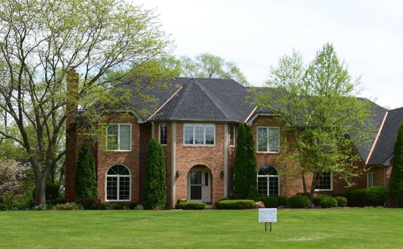 Large Brick home with asphalt shingle roof and large yard